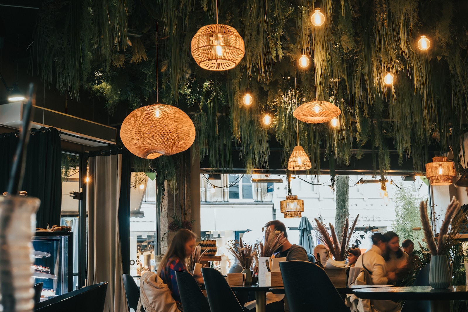 a group of people sitting at tables under lanterns