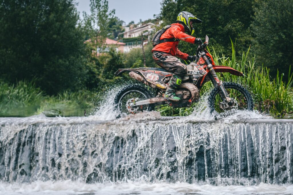 a man riding a dirt bike through a river